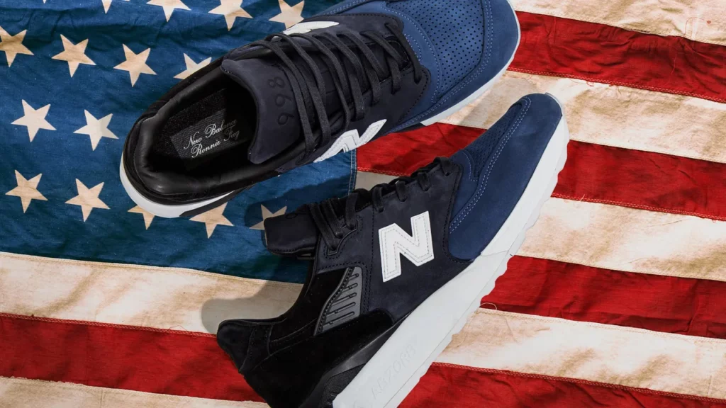 Sneakers bleues avec le N de New Balance sur leur côté, posant sur le drapeau américain.